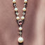 Pearl necklace with pink heart-shaped gem and silver accents on a white background