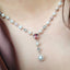 Pearl necklace with pink heart-shaped gem and silver accents on a white background