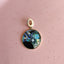 Gold pendant with a colorful circular stone on a white background