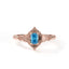 Rose gold ring with a blue gemstone on a white background