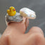 A silver lucky duck ring, the duck is set on a blue stone with a pearl cloud on the other end of the ring. 
