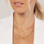 Close-up of a person wearing a gold necklace against a white background