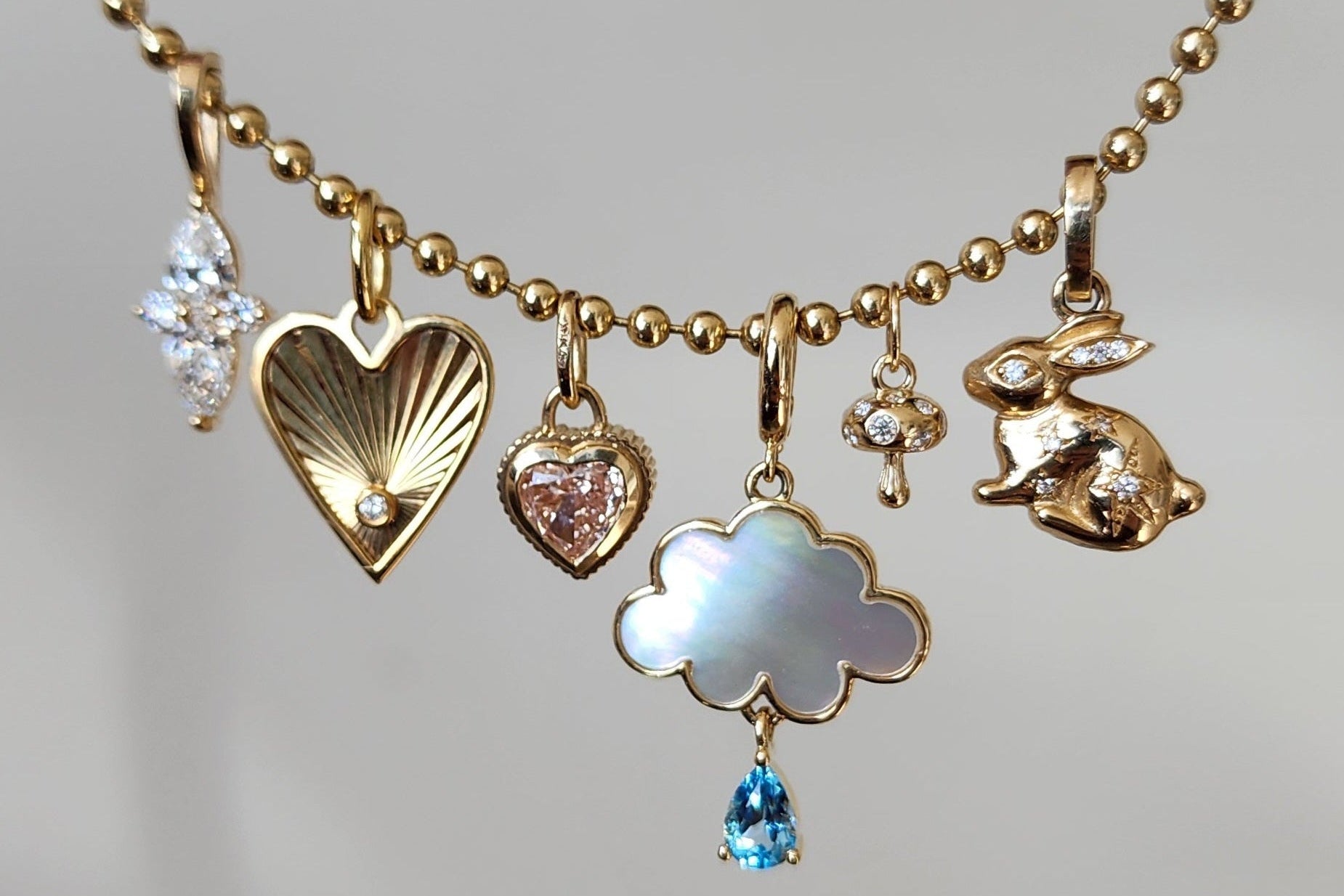 an assorted styles of charms on a gold ball chain