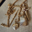 Gold jewelry set with various pieces on a beige surface