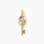 A gold key-shaped pendant featuring a flower head with a clear gemstone center, suspended from a delicate gold chain against a plain white background.