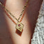 Two gold pendants with red gemstones on a textured surface