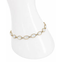 Gold bracelet with white stones on a mannequin hand against a white background