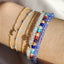 Close-up of a wrist wearing multiple colorful beaded bracelets on a neutral background