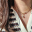 Close-up of a gold necklace with a pendant worn by a person.