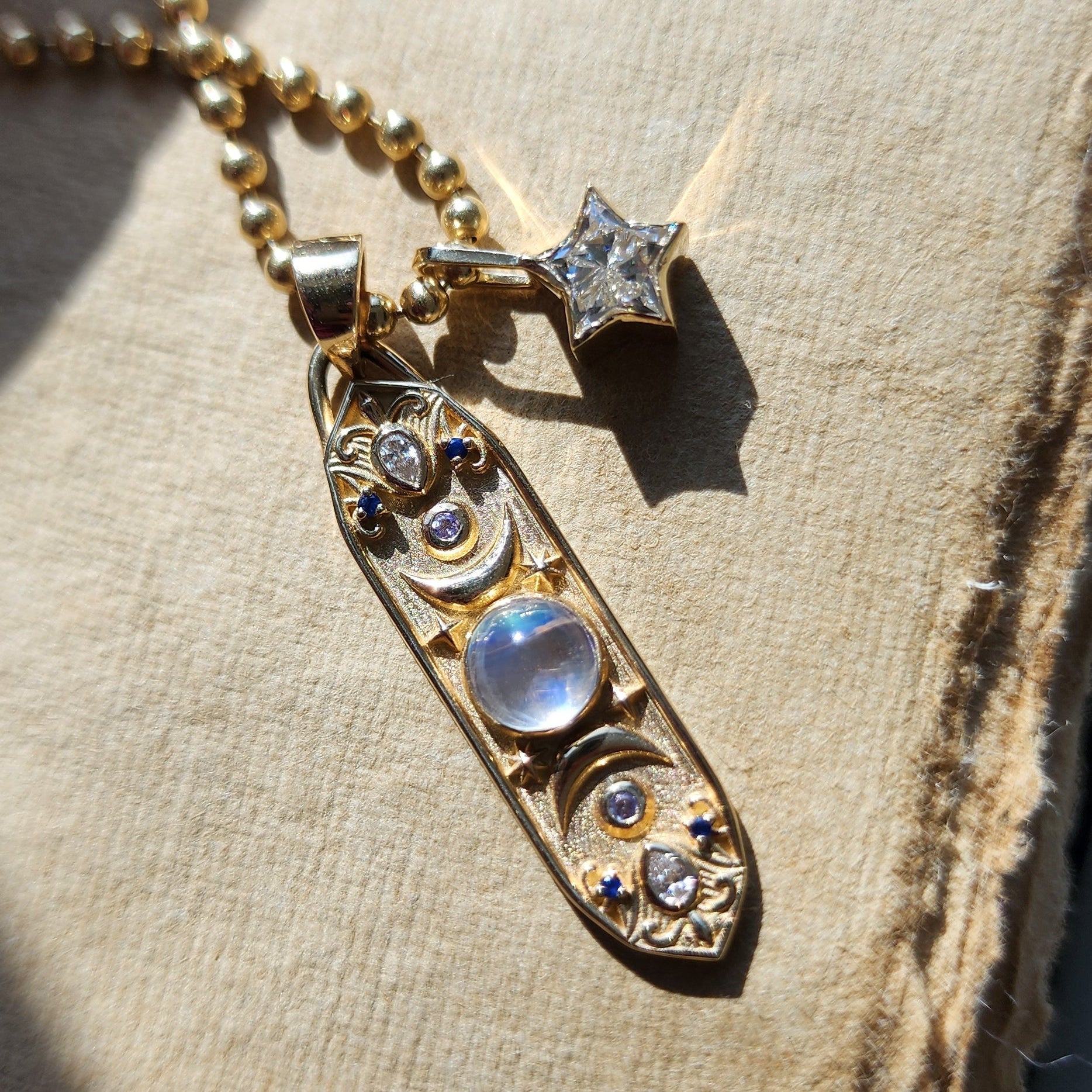 diamond star and moon phase charm on a gold ball chain