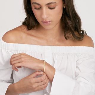 A gold bangle bracelet with ribbed square pattern. Very classic and looks best stacked. 