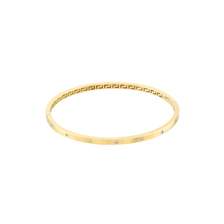 A solid yellow gold hinge bangle with snap closure. The front features seven diamonds evenly spaced out. 