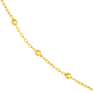 Solid yellow gold beaded station chain with a gold beaded accent evenly spacing out on a cable chain. Close up