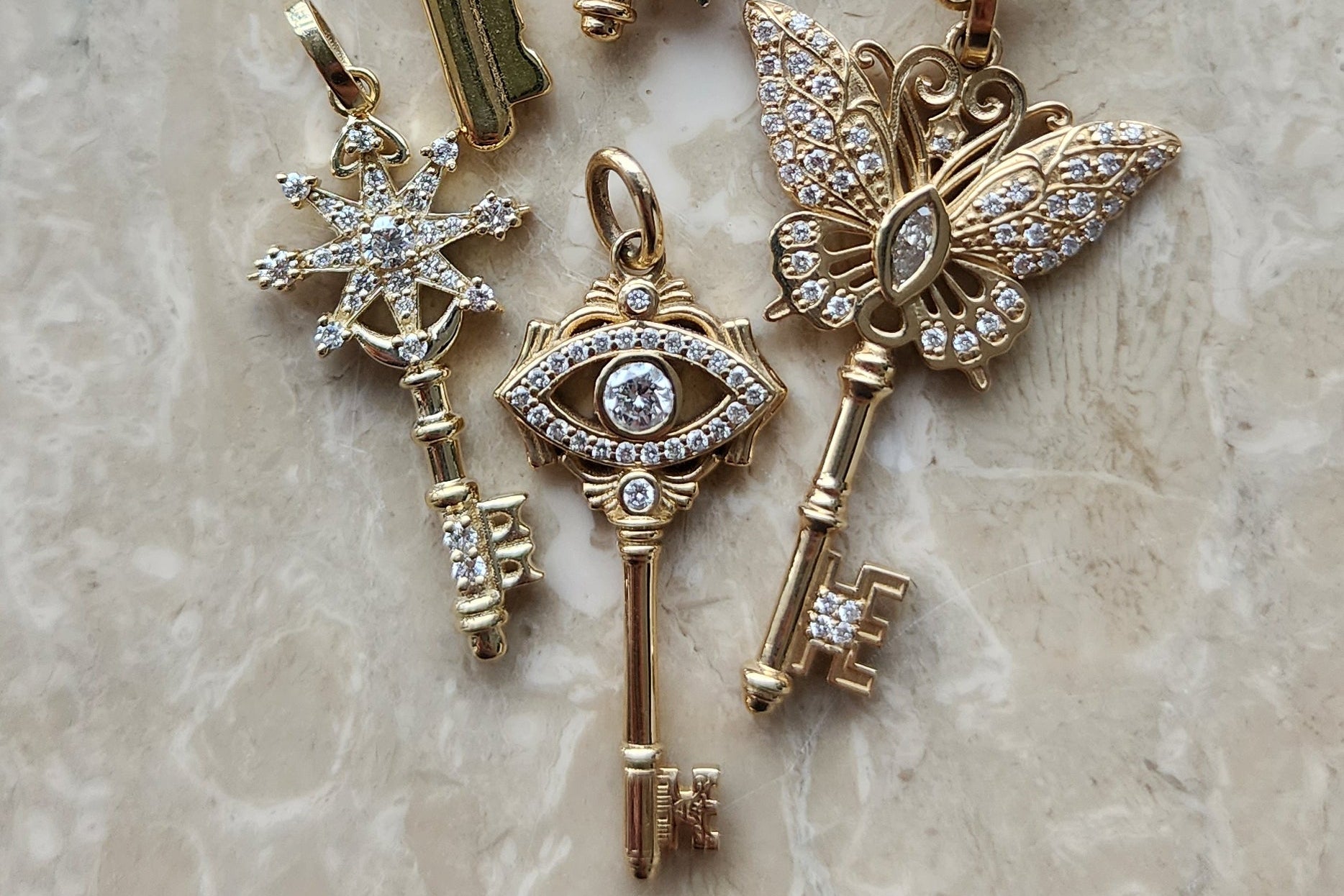 Gold key-shaped jewelry on a marble surface