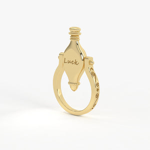 Gold ring with a decorative top and 'Luck' engraved on a white background