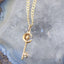 Gold necklace with a key-shaped pendant on a geode background