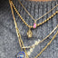 Gold necklaces with various pendants on a textured surface