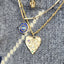 Gold necklaces with various pendants on a textured surface