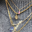 Gold necklaces with various pendants on a textured surface