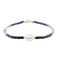 A faceted ombre beaded necklace with a large oval pearl in the center with two accent beads and round clasp. 