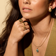 An oval pendant with a faceted colored center stone and a halo. There are eleven colored gemstone in the halo creating a vintage look. 