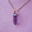 Necklace with a purple crystal pendant on a pink background
