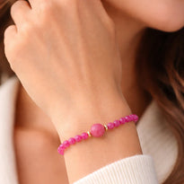 Close-up of a wrist wearing a pink beaded bracelet with a blurred background