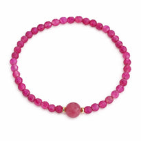 Pink beaded bracelet with a gold accent on a white background