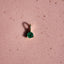 Heart-shaped emerald gemstone on a pink background