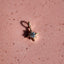 Star-shaped earring with a central gemstone on a pink textured background