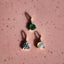 Three gemstone earrings on a pink textured surface