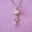 Gold rose-shaped pendant necklace on a pink background