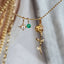 Gold necklace with green gemstone on a soft background
