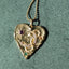Gold necklaces with various pendants on a textured surface