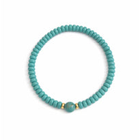 Turquoise beaded bracelet with a gold accent on a white background