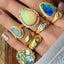 A roundish triangle shaped boulder opal that has blue and green hues and lots of fire. This ring is bezel set and framed with gold border with diamond accents. 
