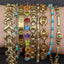 A stack of vintage bracelets including the featured product of a white gold emerald and diamond bar bracelet. 