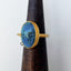 A large oval blue turquoise stone bezel set in gold vermeil. On the side it has a diamond shaker to add uniqueness to the design. Simple tube band. 