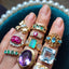 Showing a variety of vintage rings available stacked on the finger, including the solid gold diamond and emerald alternate band. 